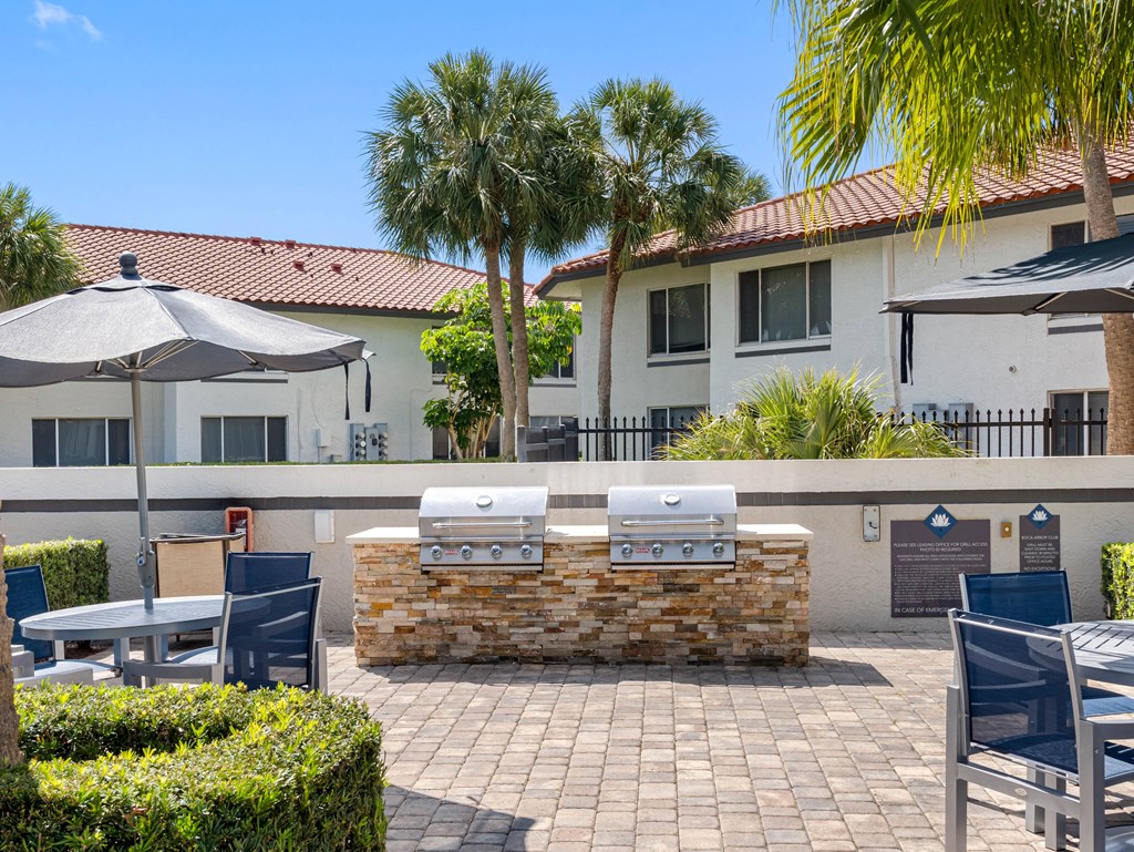 A patio with a stone wall and a grill.